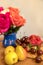 Fruits plate on the table with many roses in blue vase . Selective focus on pear and cherry in the front