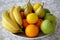 Fruits on the plate. Various of delicious fruits full of vitamins and antioxidant, yellow lemons and bananas, green apples and