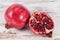 Fruits of red pomegranate, whole and sectioned, on wooden plank