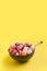 Fruits salad of melon, watermelon, blueberry in coconut bowl on yellow background. Healthy breakfa Clean eating. Vertical