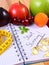 Fruits, tablets supplements and centimeter with notebook, slimming and healthy food