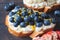 Fruity vegetarian toasts for breakfast on dark background. Bread slices with ricotta, berries, banana, chocolate and seeds