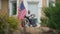 Frustrated African American disabled man sitting in wheelchair holding soccer ball. National flag fluttering on house