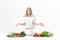 Frustrated blond woman spreads hands in both directions and lots of fresh vegetables on white background