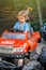 Frustrated boy sits in red children car in public park