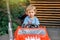 Frustrated boy sits in red children car in public park