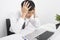 Frustrated businessman with head in hands sitting at desk in office