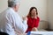 A frustrated crying woman holds her palms over face at a session with a male psychologist. Mature psychotherapist