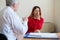 A frustrated crying woman holds her palms over face at a session with a male psychologist. Mature psychotherapist