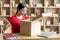 Frustrated disappointed young japanese lady opens cardboard box and sad for mistake with parcel