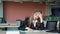 Frustrated female student sitting at the desk with a pile of study books in university library. Young college student at