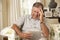 Frustrated Retired Senior Man Sitting On Sofa At Home Using Digital Tablet