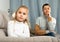 Frustrated small girl sitting at sofa, having conflict with mother