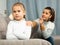 Frustrated small girl sitting at sofa, having conflict with mother