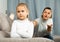 Frustrated small girl sitting at sofa, having conflict with mother