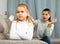 Frustrated small girl sitting at sofa, having conflict with mother