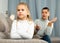 Frustrated small girl sitting at sofa, having conflict with mother