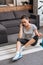 Frustrated sportswoman sitting on fitness mat and talking on smartphone