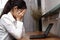 Frustrated tired young Asian woman with hands on face in workplace of office