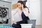 Frustrated woman on phone next to washing machine