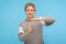 Frustrated woman with short curly hair in grey sweatshirt feeling tired and overworked, showing timeout gesture