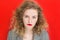 Frustrated Young blonde woman with red lips looking at camera over red background. Expressive facial emotions, lack of