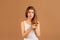 Frustrated young woman having problem with split ends on brown studio background. Beauty and wellness concept