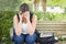 Frustrated Young Woman Sitting Alone on Bench Next to Books