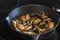 Frying chestnut mushrooms in a cast iron frying pan, on an electric stove