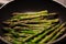 Frying green asparagus in skillet in oil