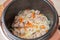 Frying meat with onions and carrots in a multicooker pan. Modern, bright multi cooker with products. Cooking pilaf with meat in