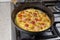 Frying pan full of omelet with cherry tomatoes and sausage slices