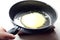 Frying pan in hand with a pancake cooking, close - up-the concept of making delicious quick home-made breakfasts