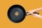 Frying Pan Held by Female Hands on Orange Background