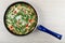 Frying pan with omelet with spinach, sweet pepper, green peas on table. Top view