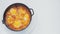 Frying pan with shakshuka rotates in a circle on a white background