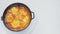 Frying pan with shakshuka rotates in a circle on a white background