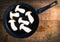 Frying pan with sliced king trumpet mushrooms on a background of wood