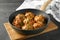 Frying pan with tasty sausage balls on wooden board