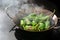 Frying peppers de padron or green pimientos in a steaming pan on a black stove. Traditional Spanish tapa or appetizer dish, copy