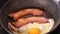 Frying pork bacon strips and egg in a black pan