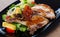 Frying pork loin at plate with salad from avocado, tomatoes and corn salad