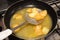 Frying rounded potatoes on a black pan with boiling oil