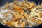 Frying slices of chanterelles mushroom, a close look, bubbles of olive oil over the slices.