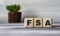 FSA - word on wooden cubes against the background of a light board with beautiful divorces and a cactus