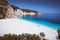 Fteri beach, Kefalonia, Greece. Lonely tourists protected from sun umbrella chill relax near clear blue emerald
