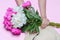 Fuchsia and white peonies bouquet and straw hat in female hands  on pink background. Flat lay composition, close up, top v