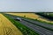 Fuel truck on the higthway driving on asphalt road among the wheat fields. seen from the air.