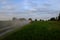 A fuel truck rushing along a dirt road leaving behind clouds of dust