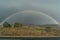 Full arch rainbow against stormy grey sky on the background